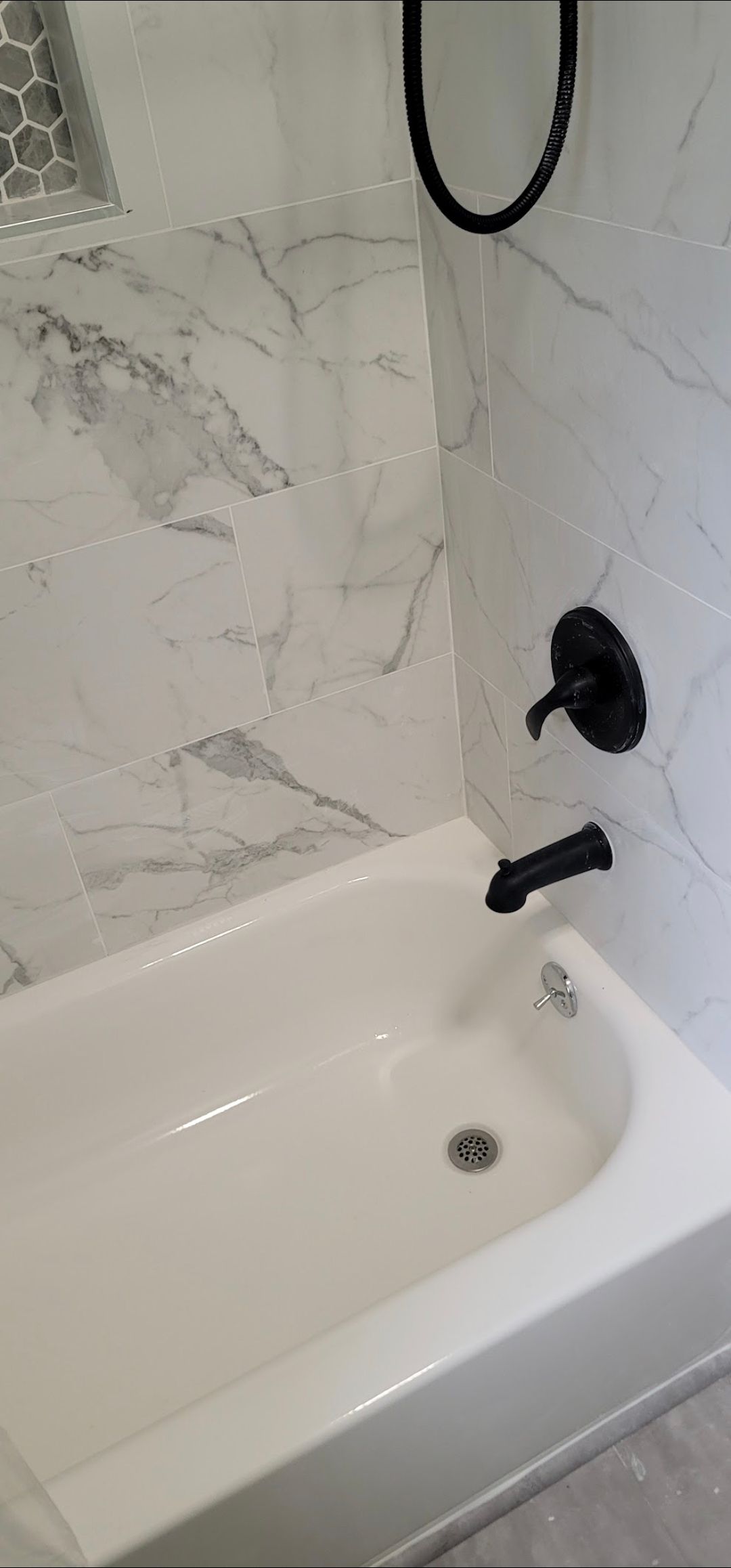 A white bathtub with a black shower head in a bathroom.