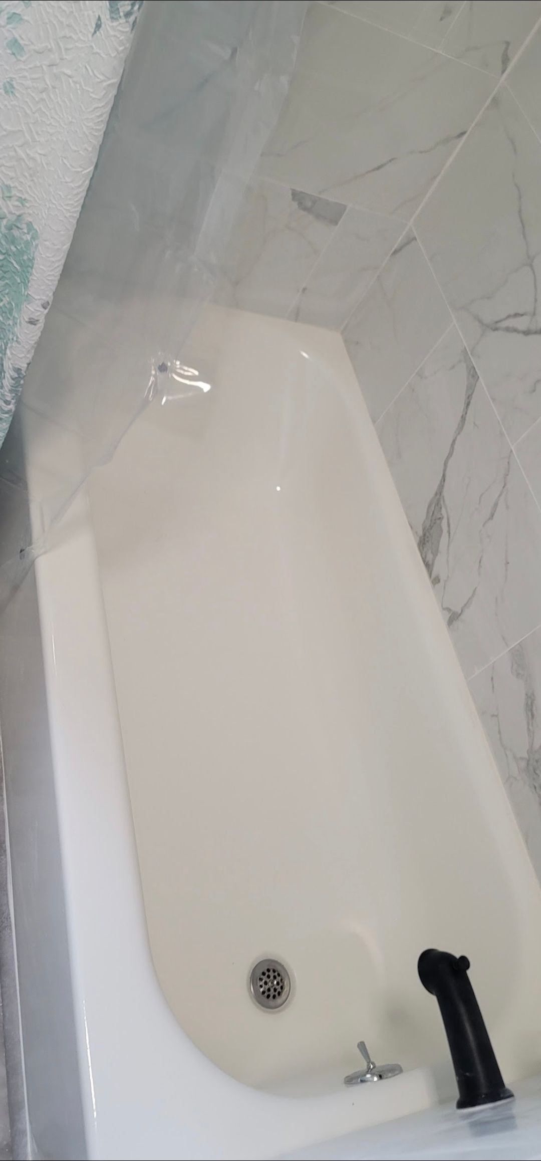 A white bathtub with a black faucet in a bathroom.
