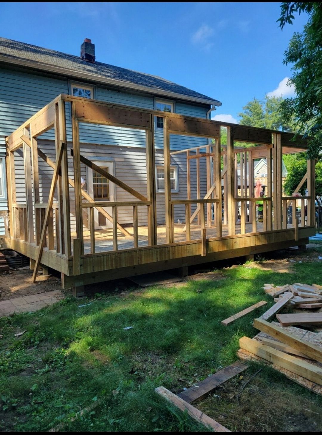 A wooden deck is being built in front of a house.
