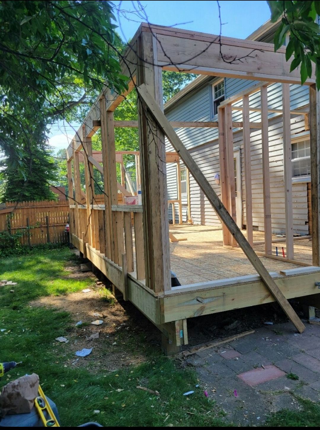 A wooden structure is being built in the backyard of a house.