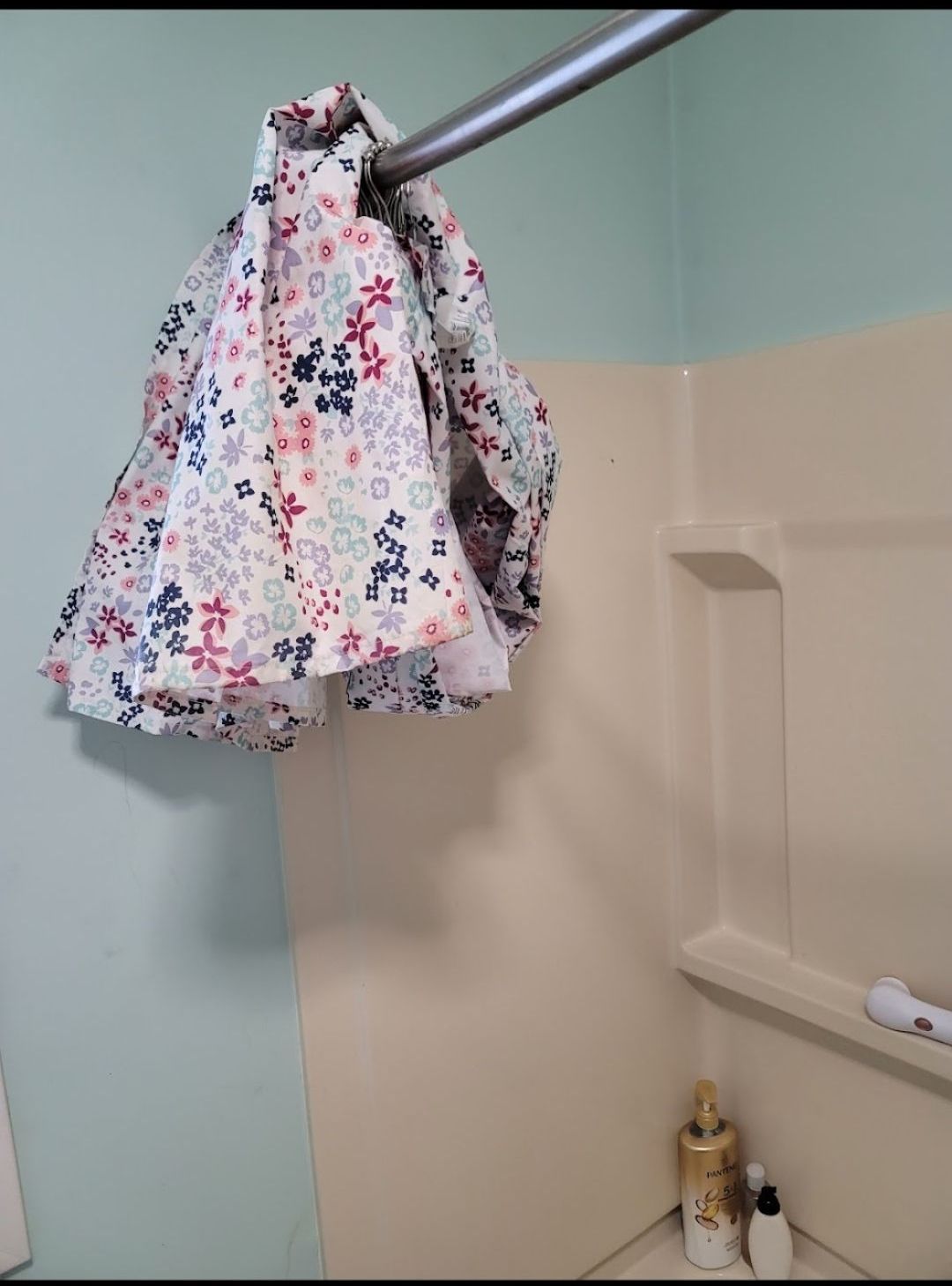 A towel is hanging from a shower curtain in a bathroom.