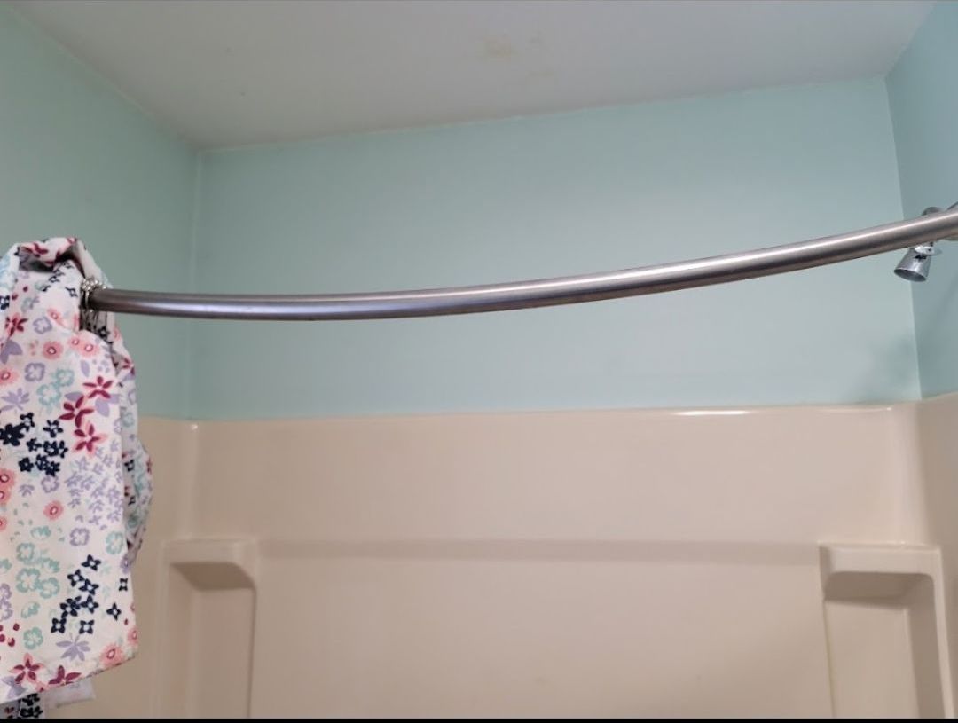 A towel is hanging from a shower curtain in a bathroom.