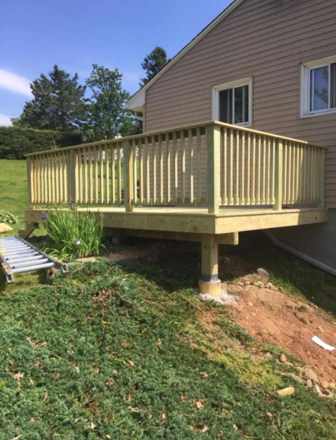 A wooden deck is sitting in front of a house.