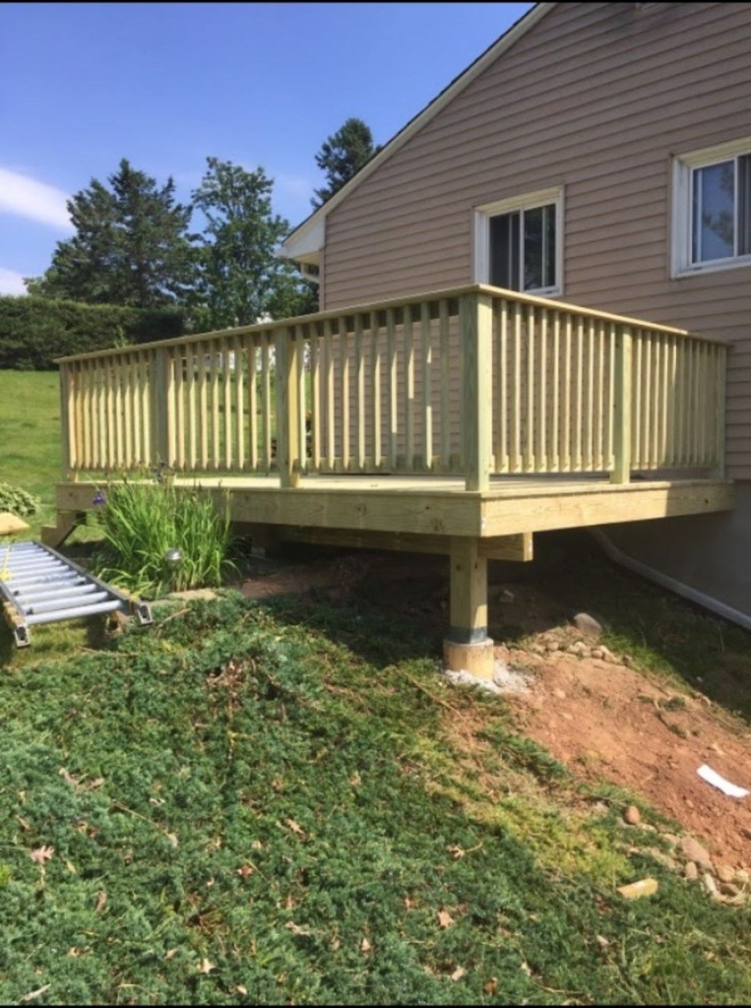 A wooden deck is sitting in front of a house.