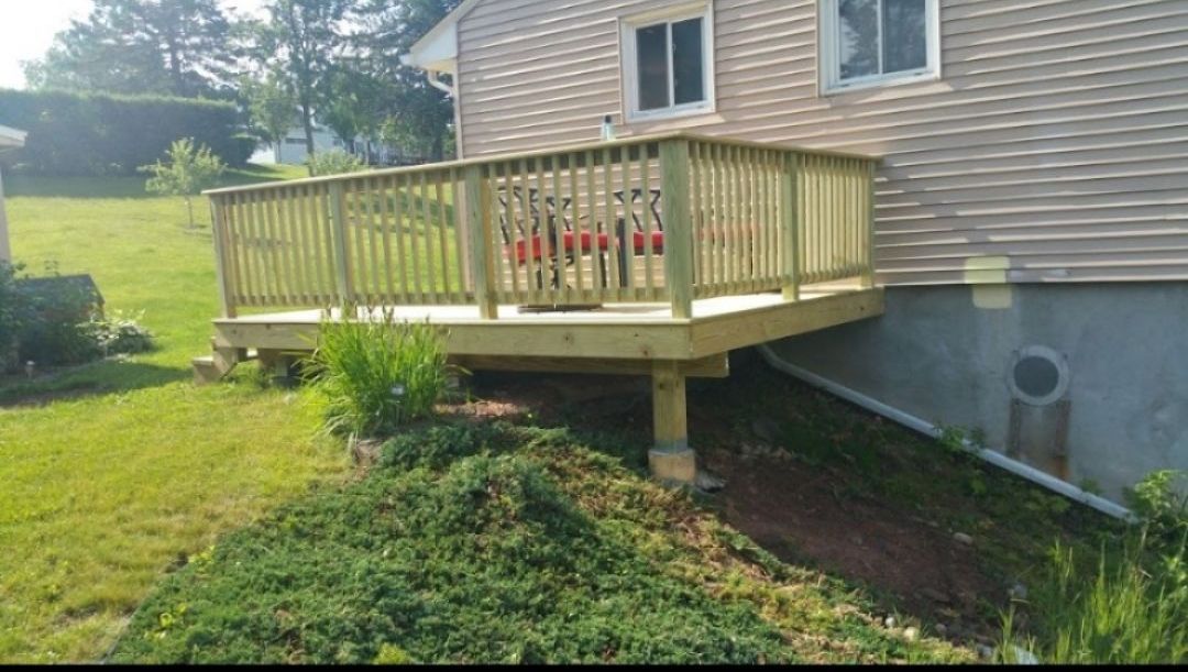 A wooden deck is sitting on the side of a house.