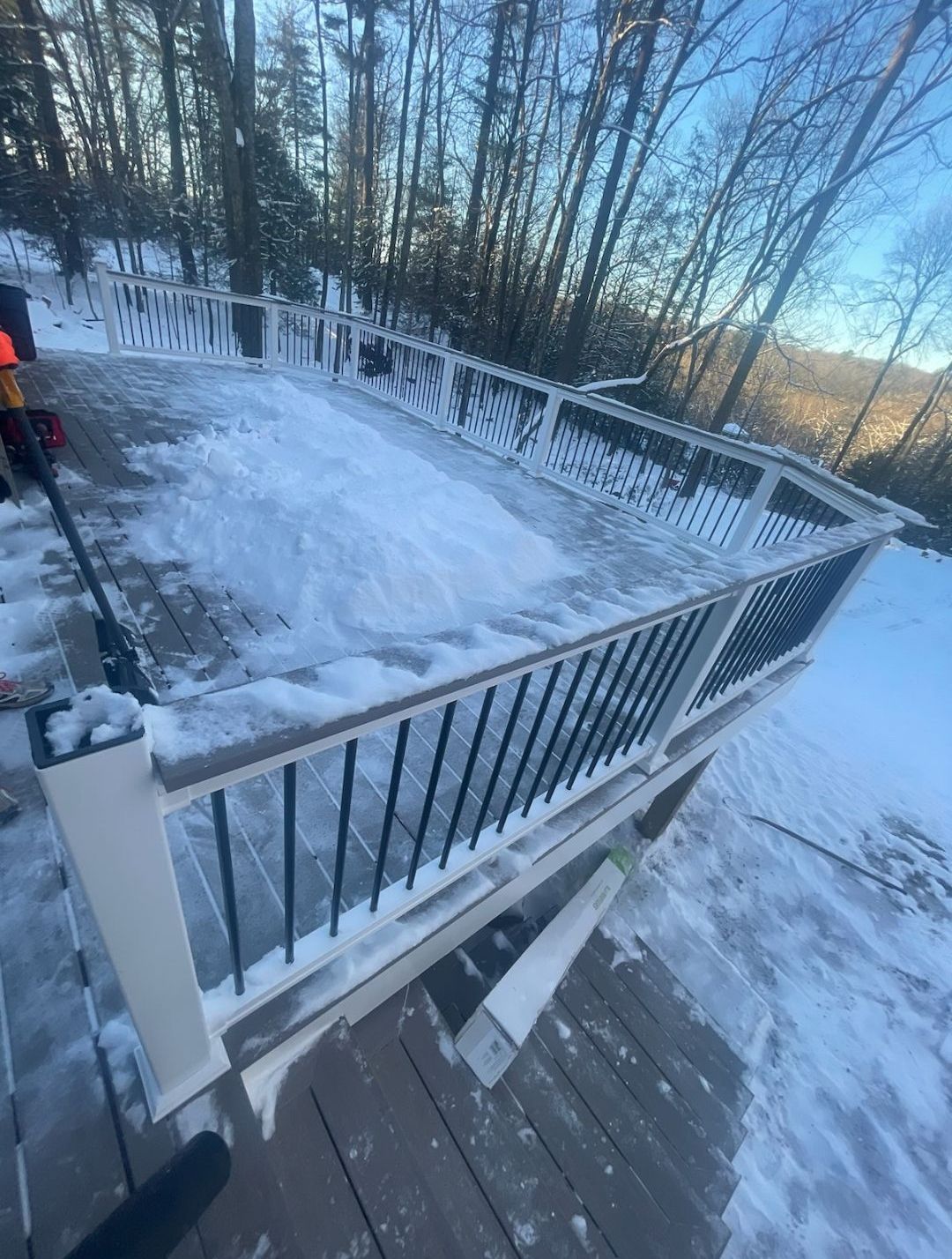 A snowy deck with a railing and a hockey stick on it.