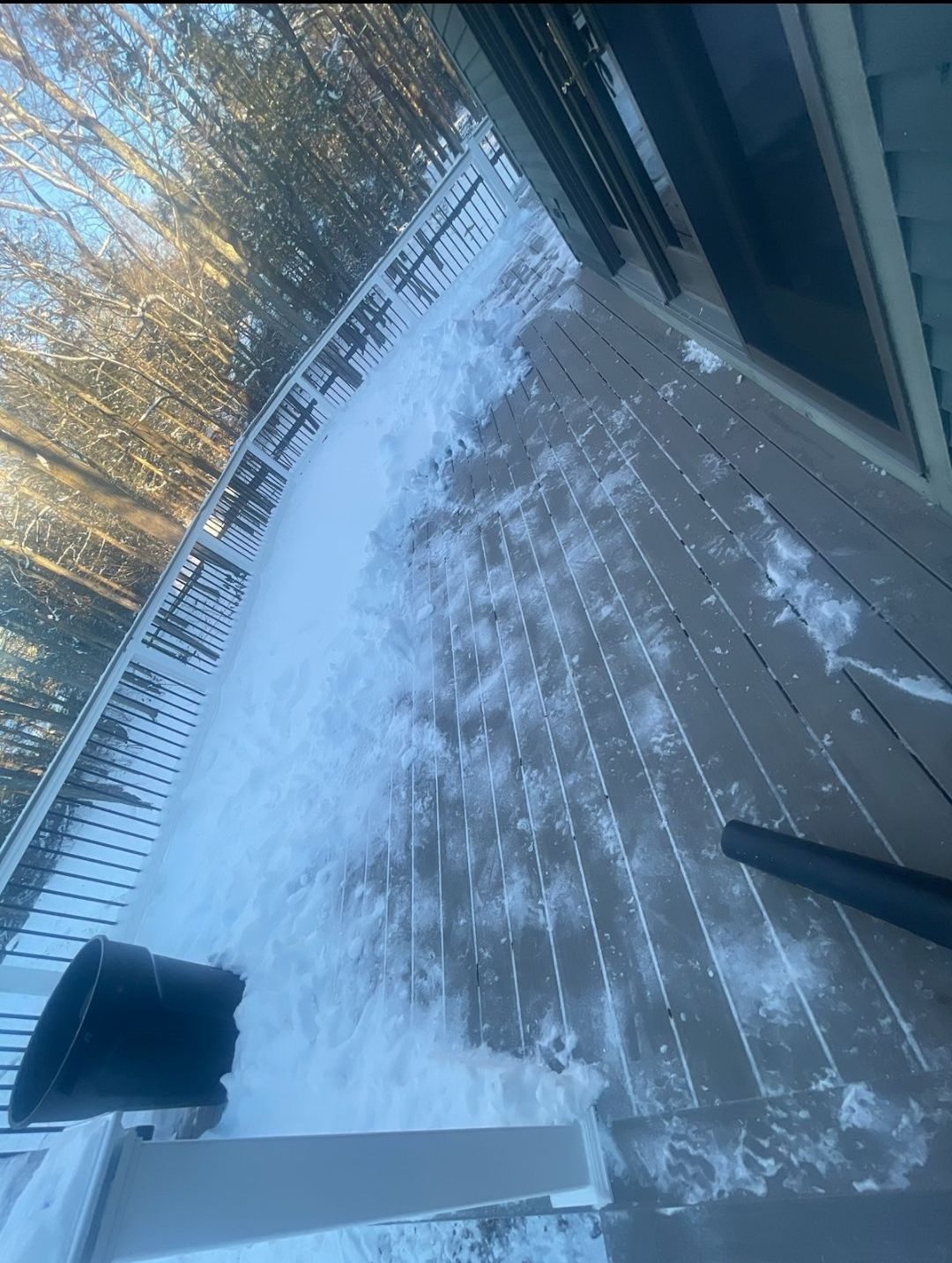 There is a lot of snow on the deck of a house.
