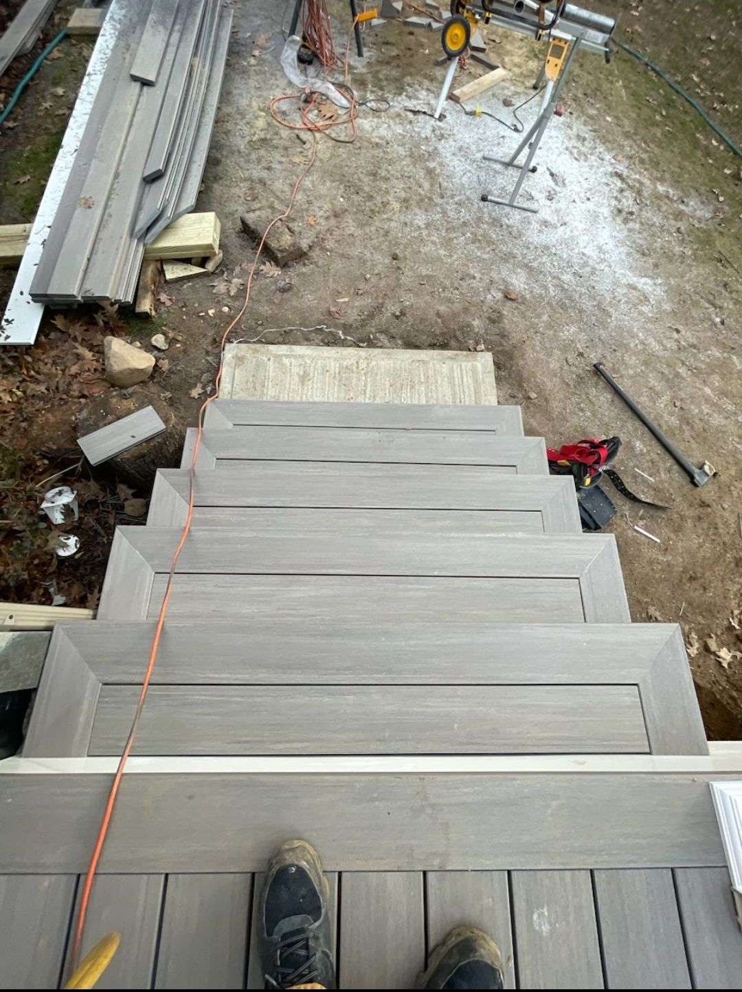 A person is standing on a wooden deck under construction.