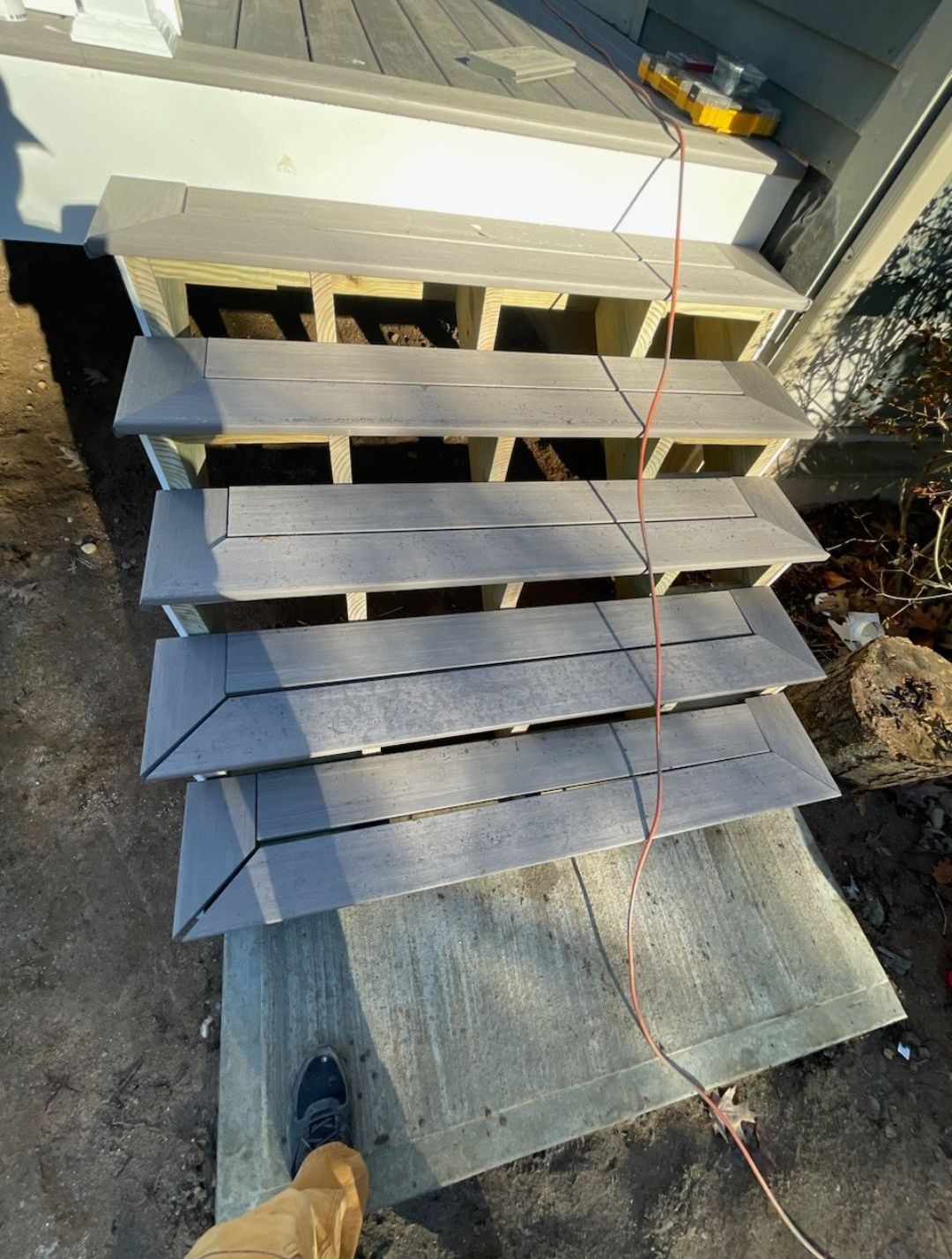 A person is standing next to a wooden staircase that is being built.