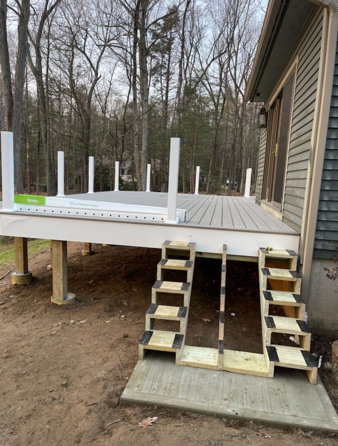 A deck with stairs leading up to it is being built on the side of a house.