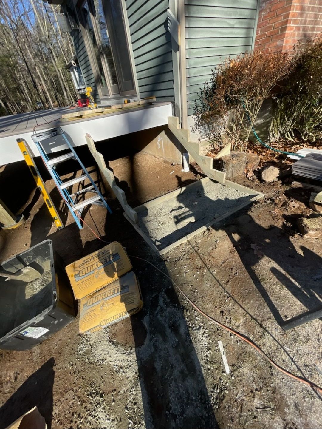 A ladder is sitting on top of a pile of dirt in front of a house.