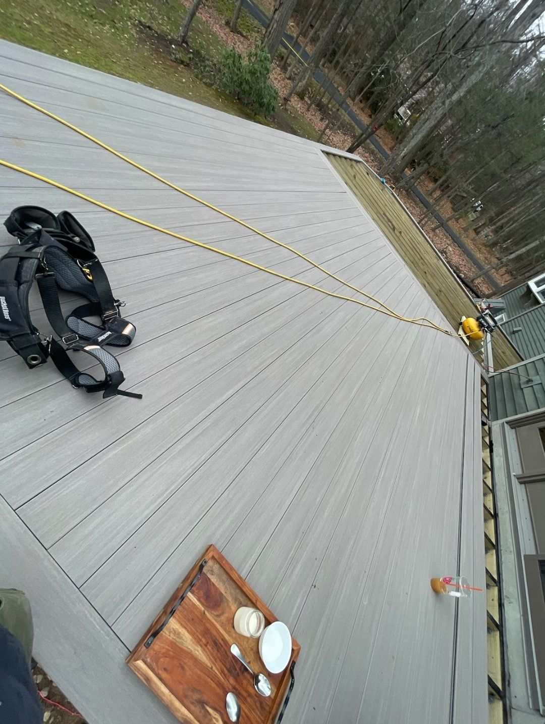 A wooden deck with a backpack and a cutting board on it.