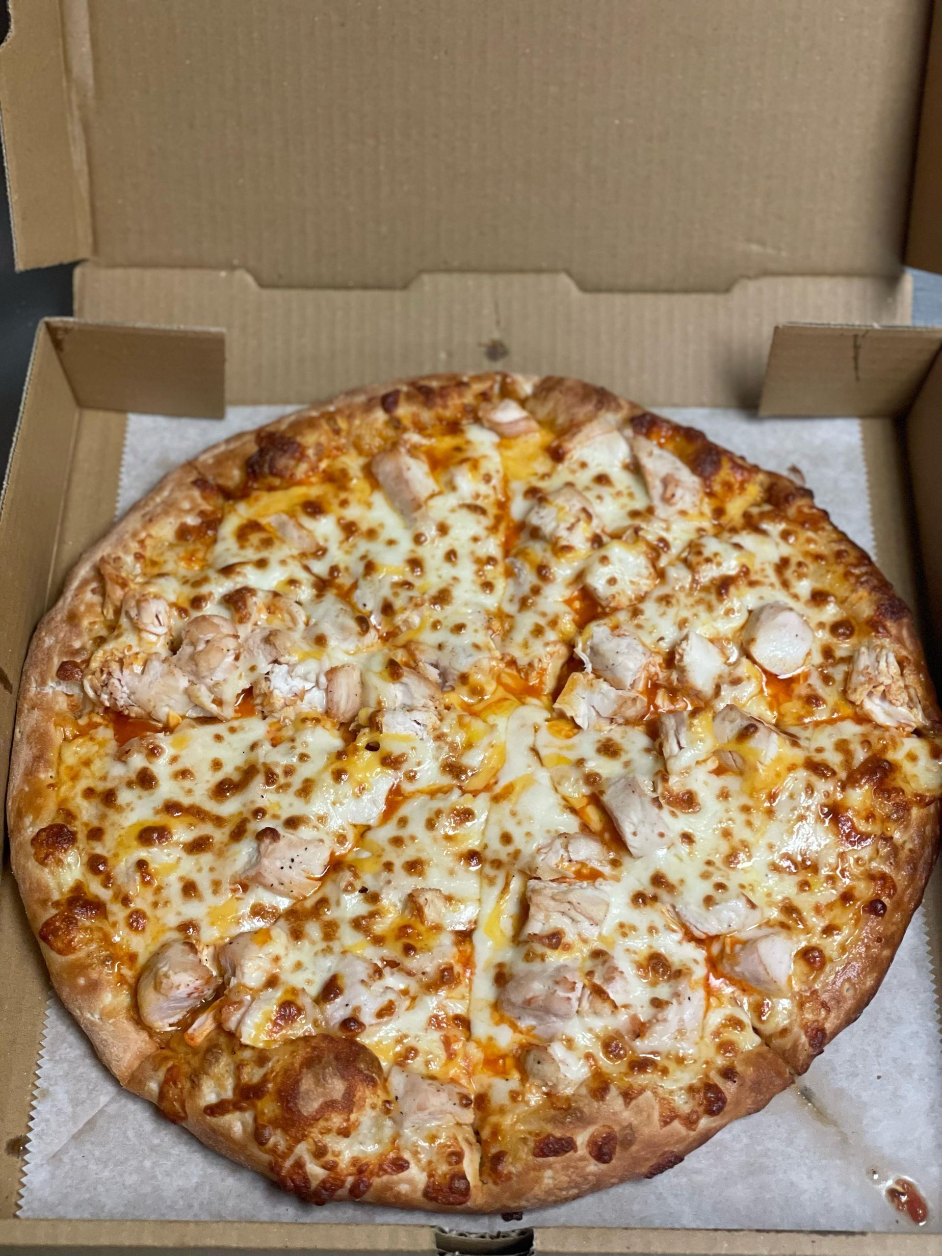 Chicken pizza in a cardboard box.