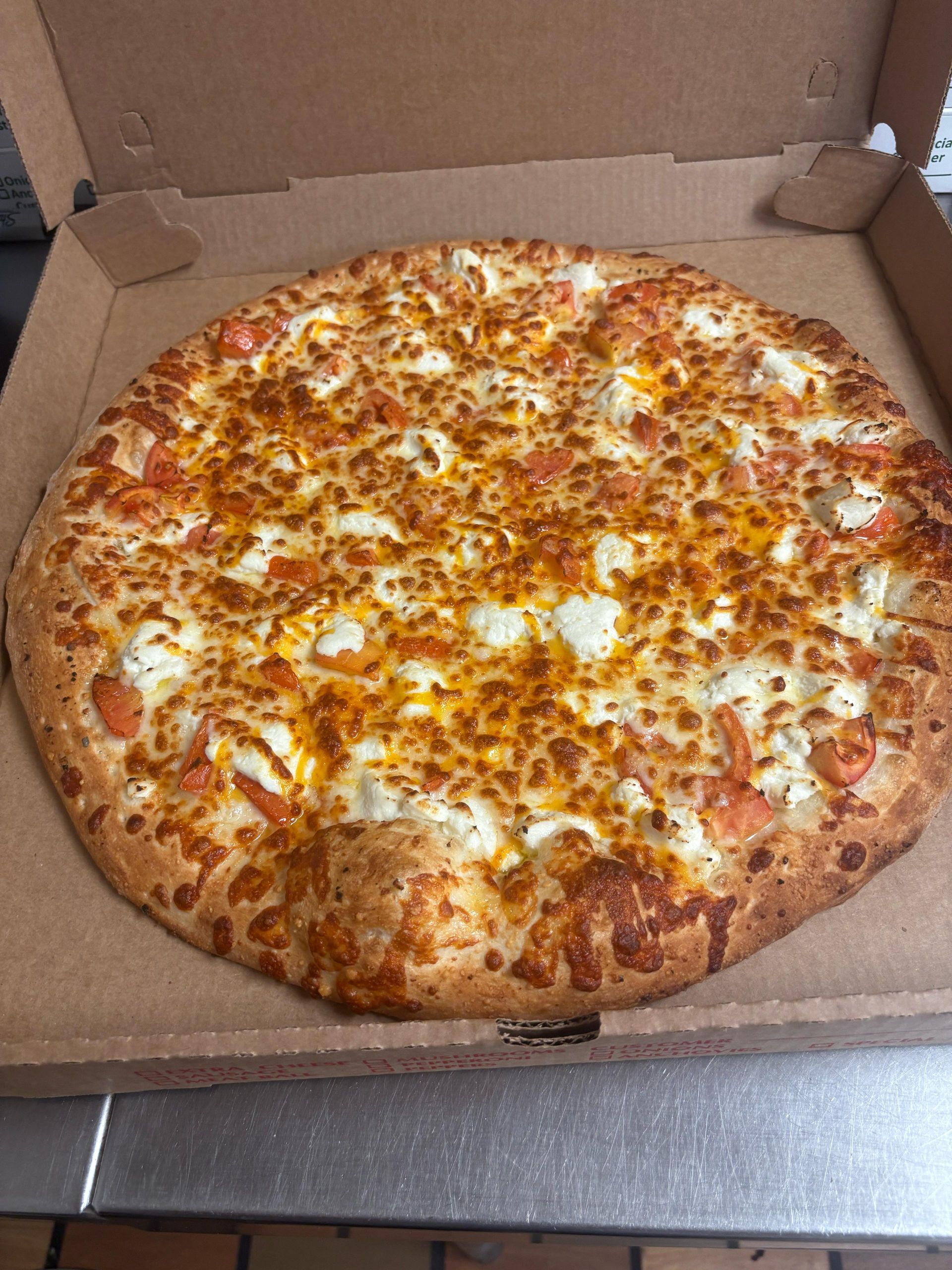 Pizza in a cardboard box, with melted cheese and red sauce visible.