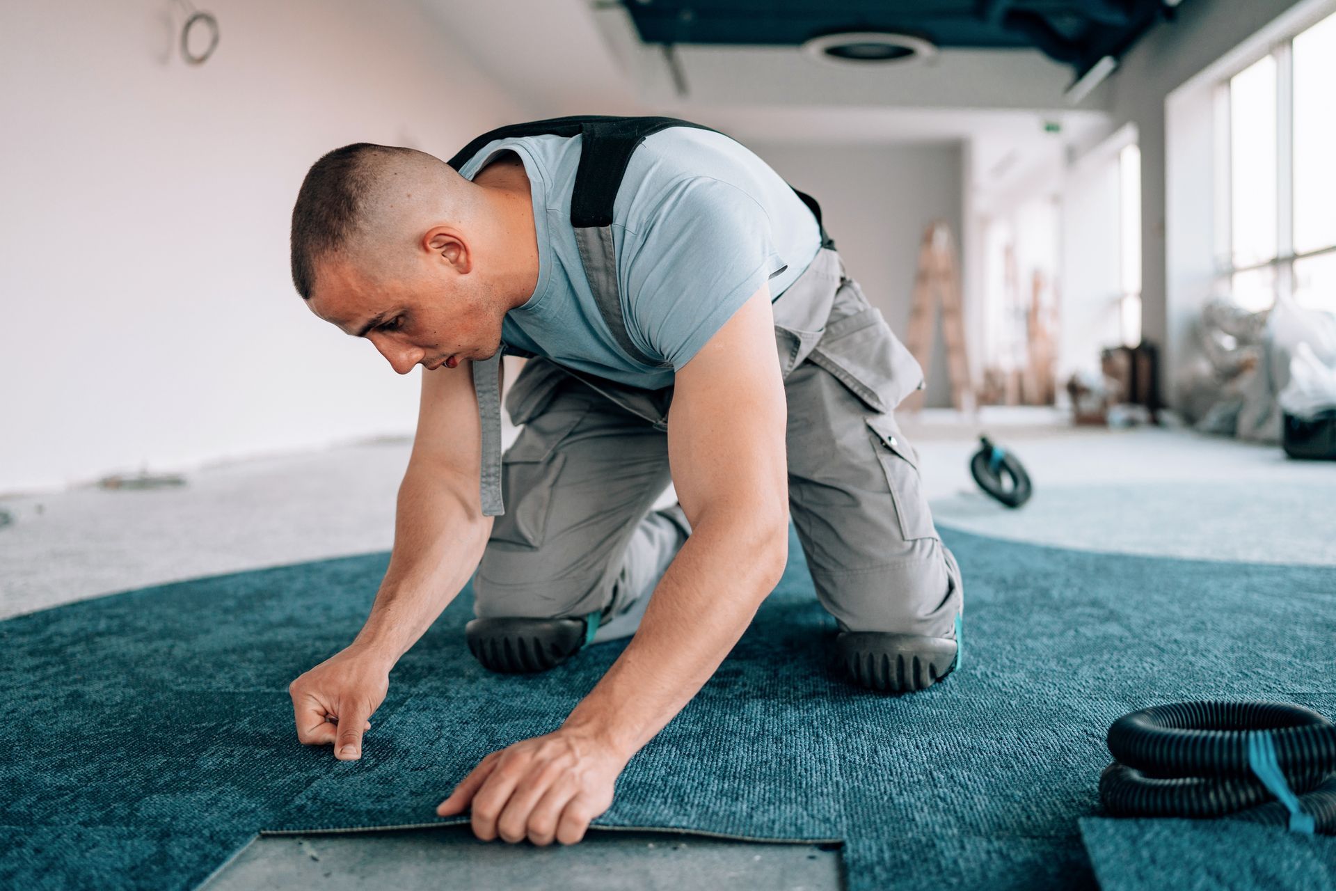 A young man installs carpets, elevating the aesthetic appeal of the business area.