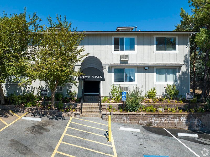 Two-story Reno Vista apartment building exterior with entry stairs, awning, and landscaping.
