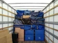 The inside of a moving truck filled with boxes and bags.