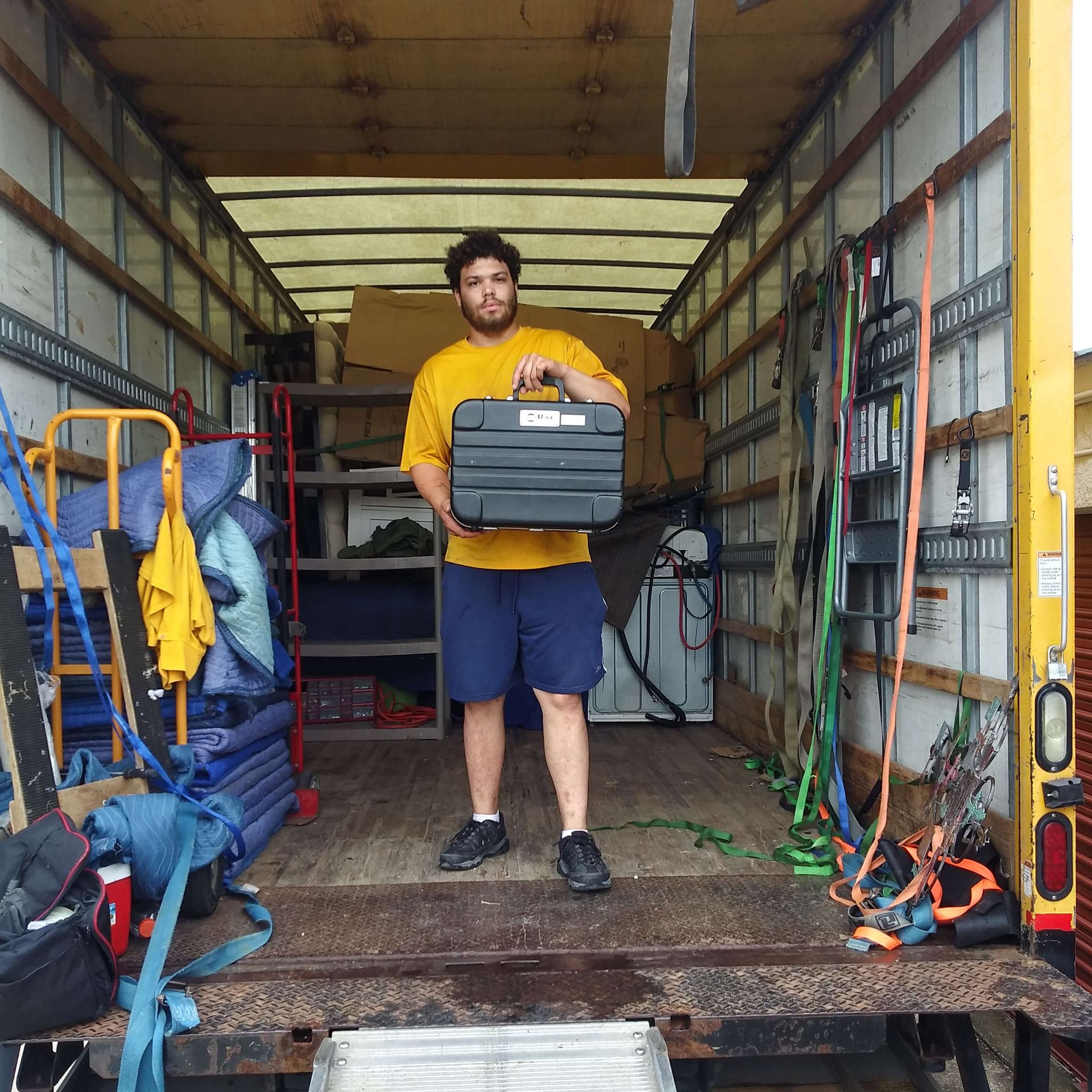 A man is standing in the back of a truck holding a toolbox