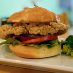 Fried chicken sandwich with tomato, red onion, lettuce, and a side of broccoli.