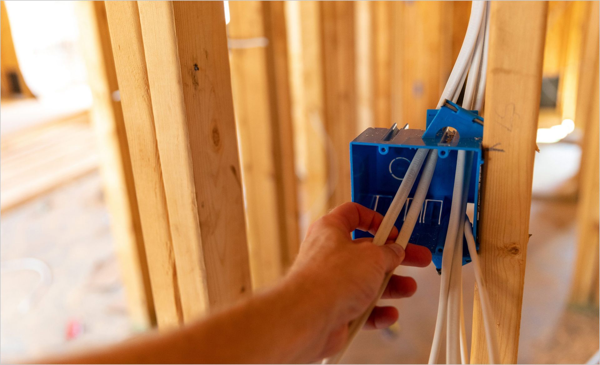 Person using a multimeter to test electrical wiring in a panel.