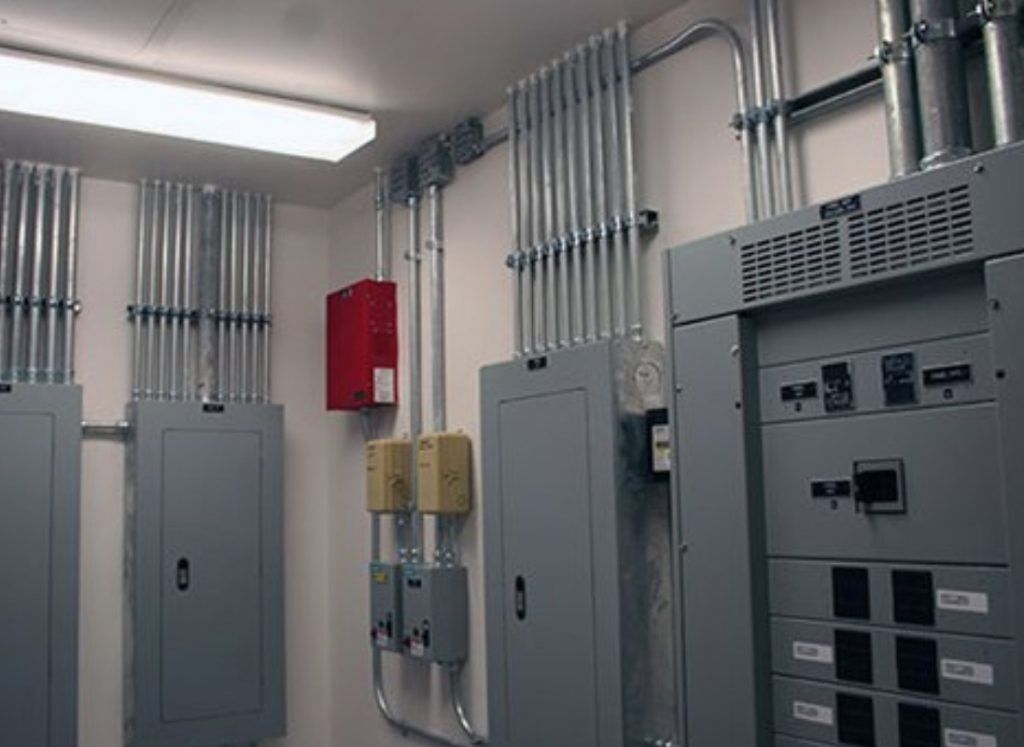 Person using a multimeter to test electrical wiring in a panel.