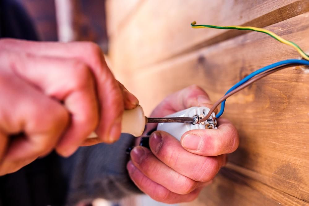 Person using a multimeter to test electrical wiring in a panel.