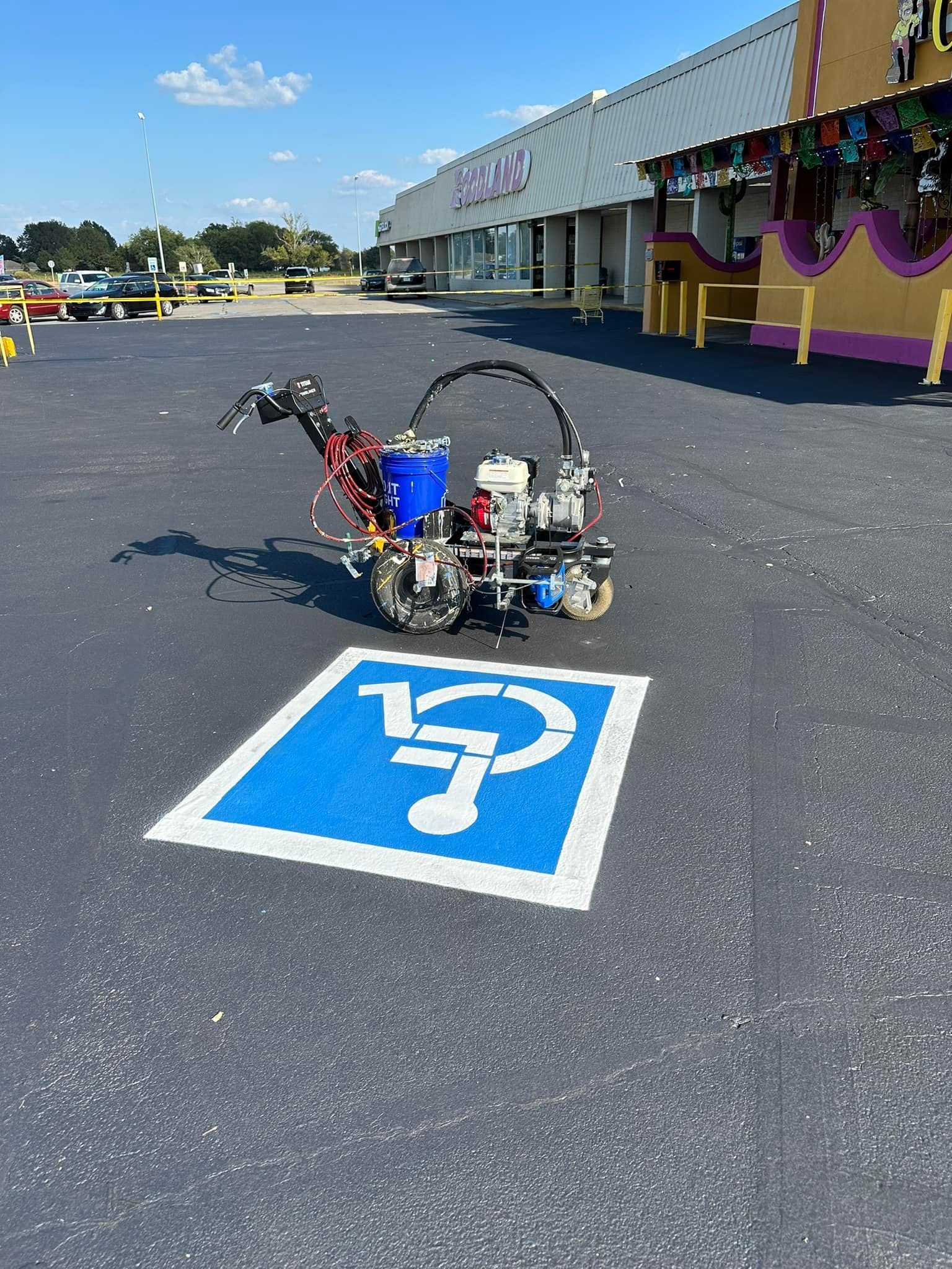 Blue handicap parking space being painted by a line striping machine in a parking lot.