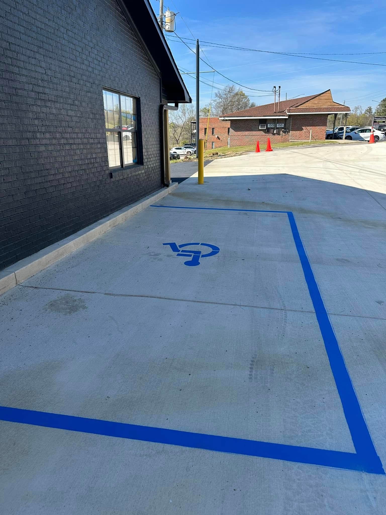 Exterior view of a building with a blue painted accessible parking space and symbol.