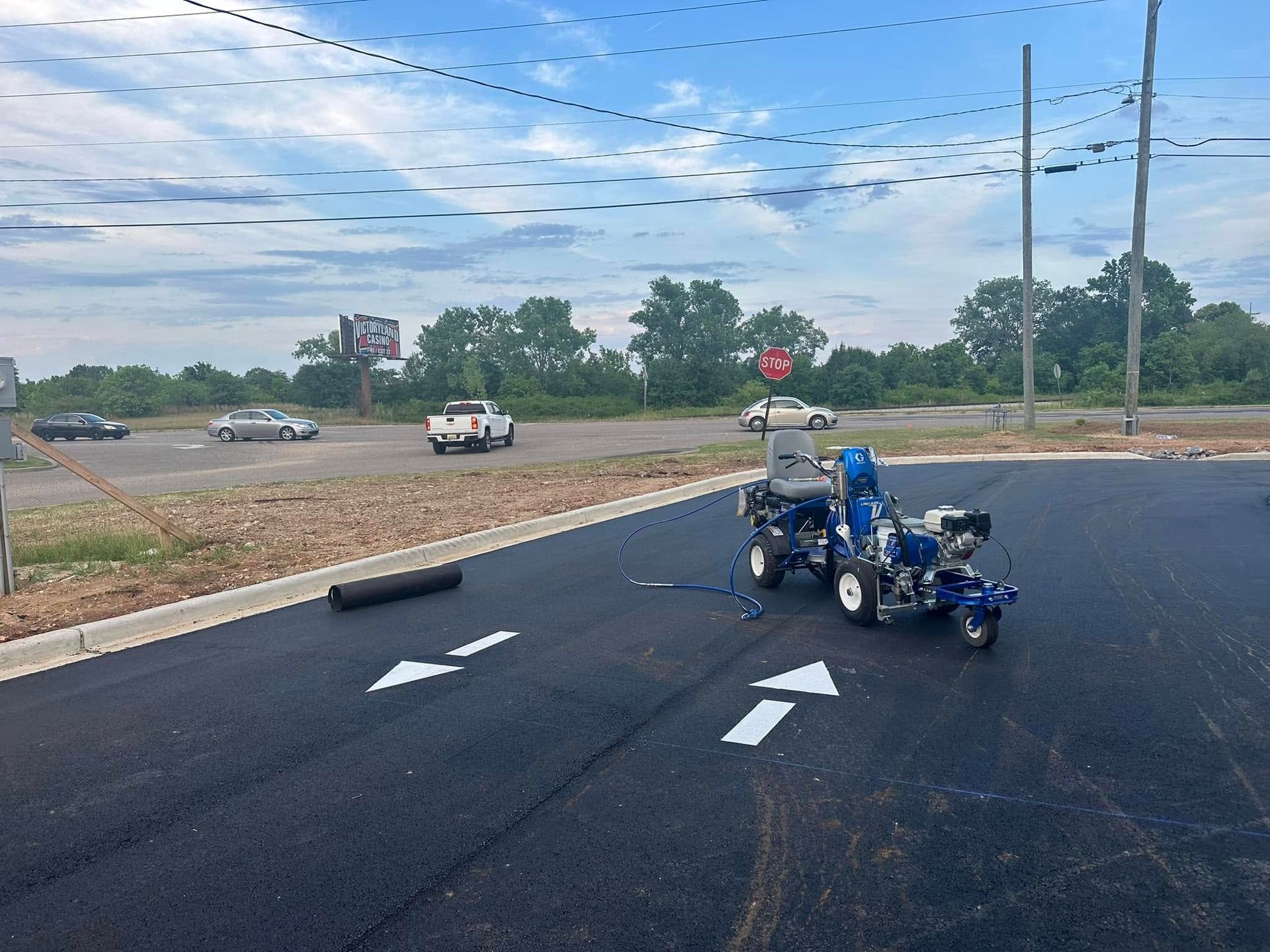 A parking lot with businesses under a clear blue sky. Red brick building on the left.