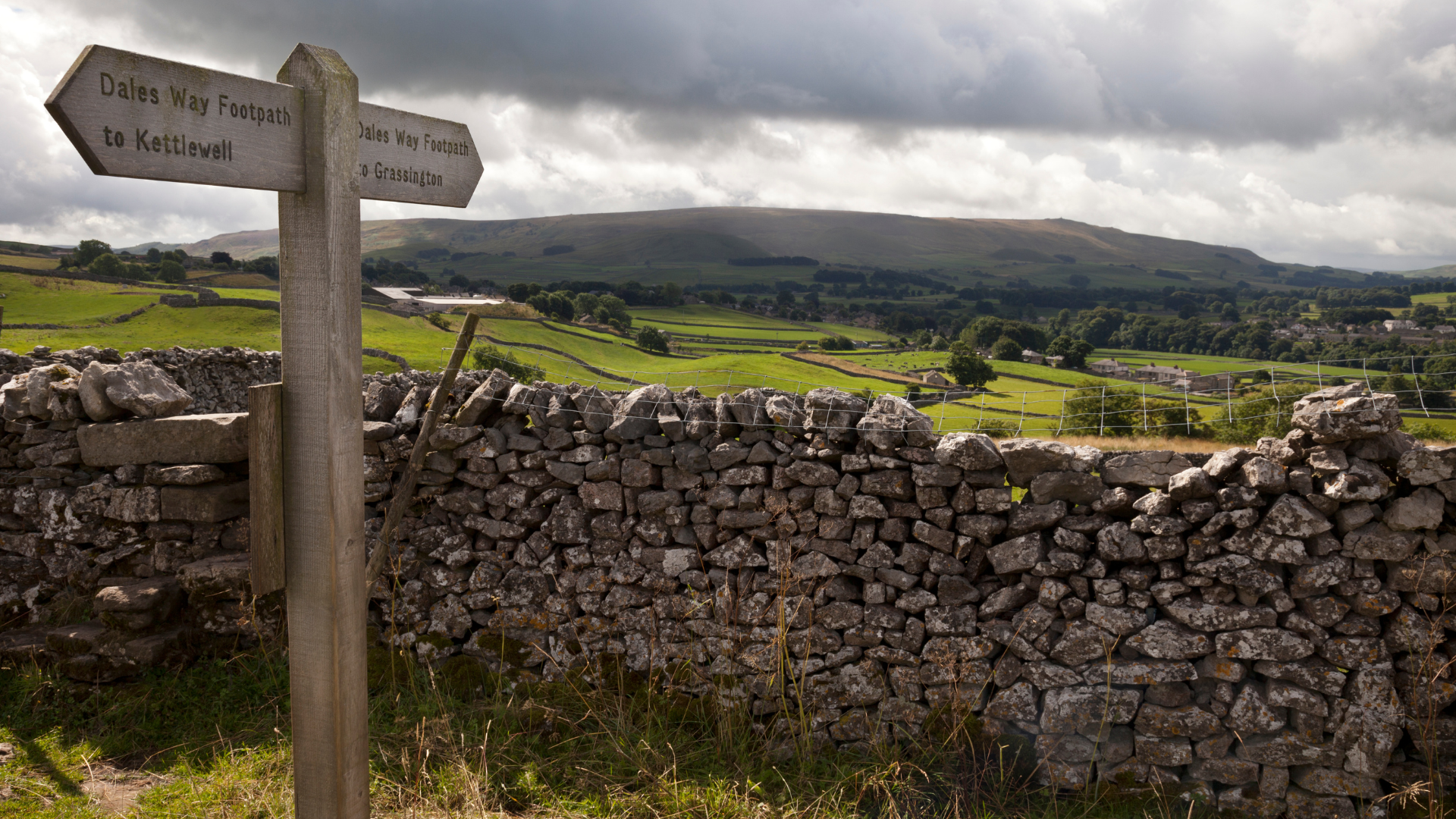 A stone wall with a wooden sign in front of it.