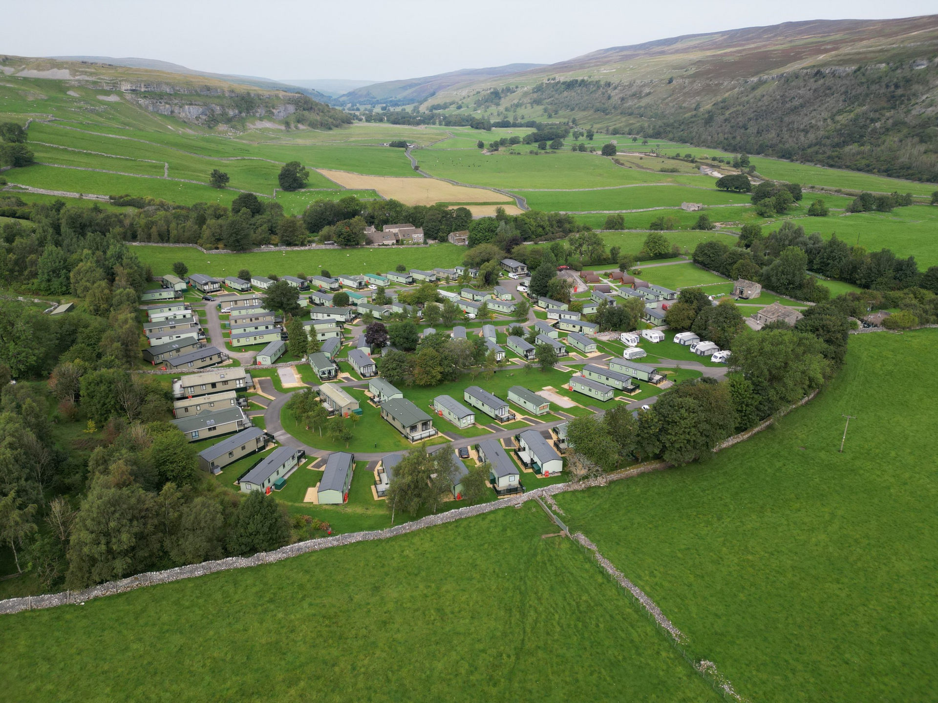 An aerial view of a residential area surrounded by lush green fields and trees.