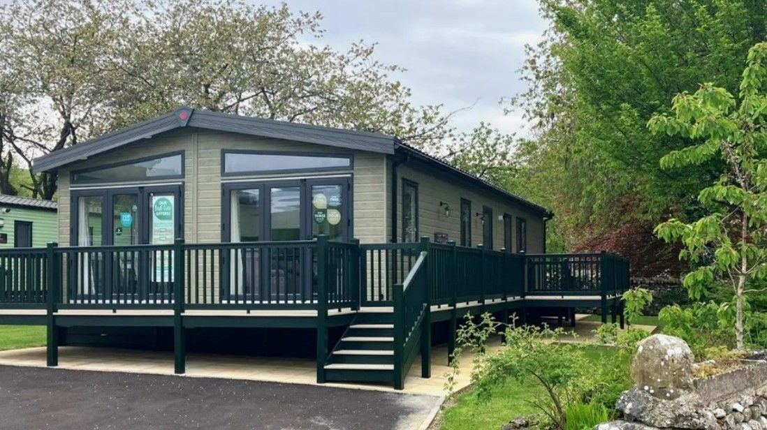 A mobile home with a large deck and stairs.