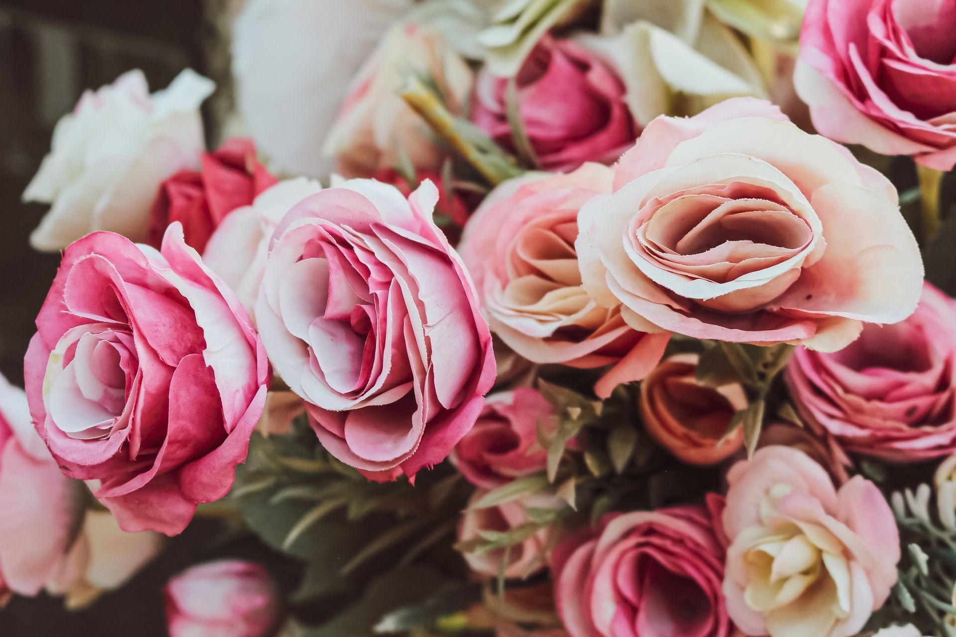 A basket filled with flowers is sitting on a wooden table.