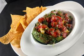 A bowl of guacamole next to a plate of tortilla chips