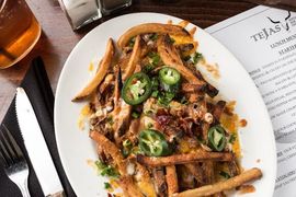 A white plate topped with french fries and jalapenos on a table.