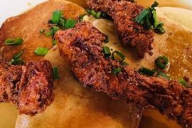 A close up of a plate of food with meat and green onions on a table.