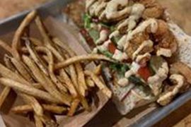 A close up of a sandwich and french fries on a table.