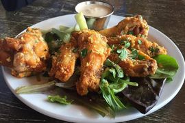 A white plate topped with chicken wings and lettuce on a table.