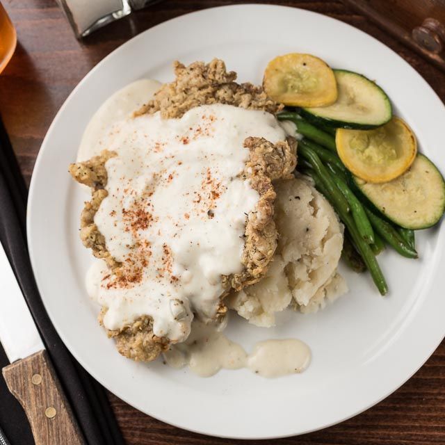 A white plate topped with chicken mashed potatoes and green beans