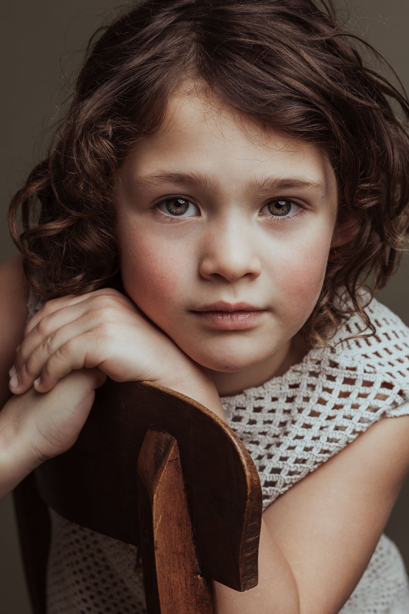 Sibbe kinderportret Portret van een meisje met krullen en groene ogen die recht in de camera kijken