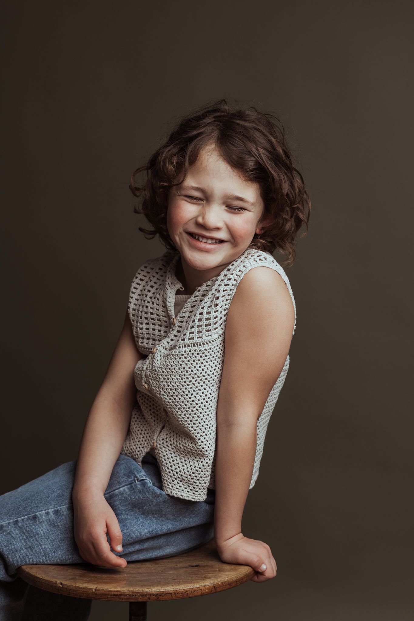 Sibbe kinderportret Portret van een kindje op een kruk dat hardop moet lachen met de ogen dicht.