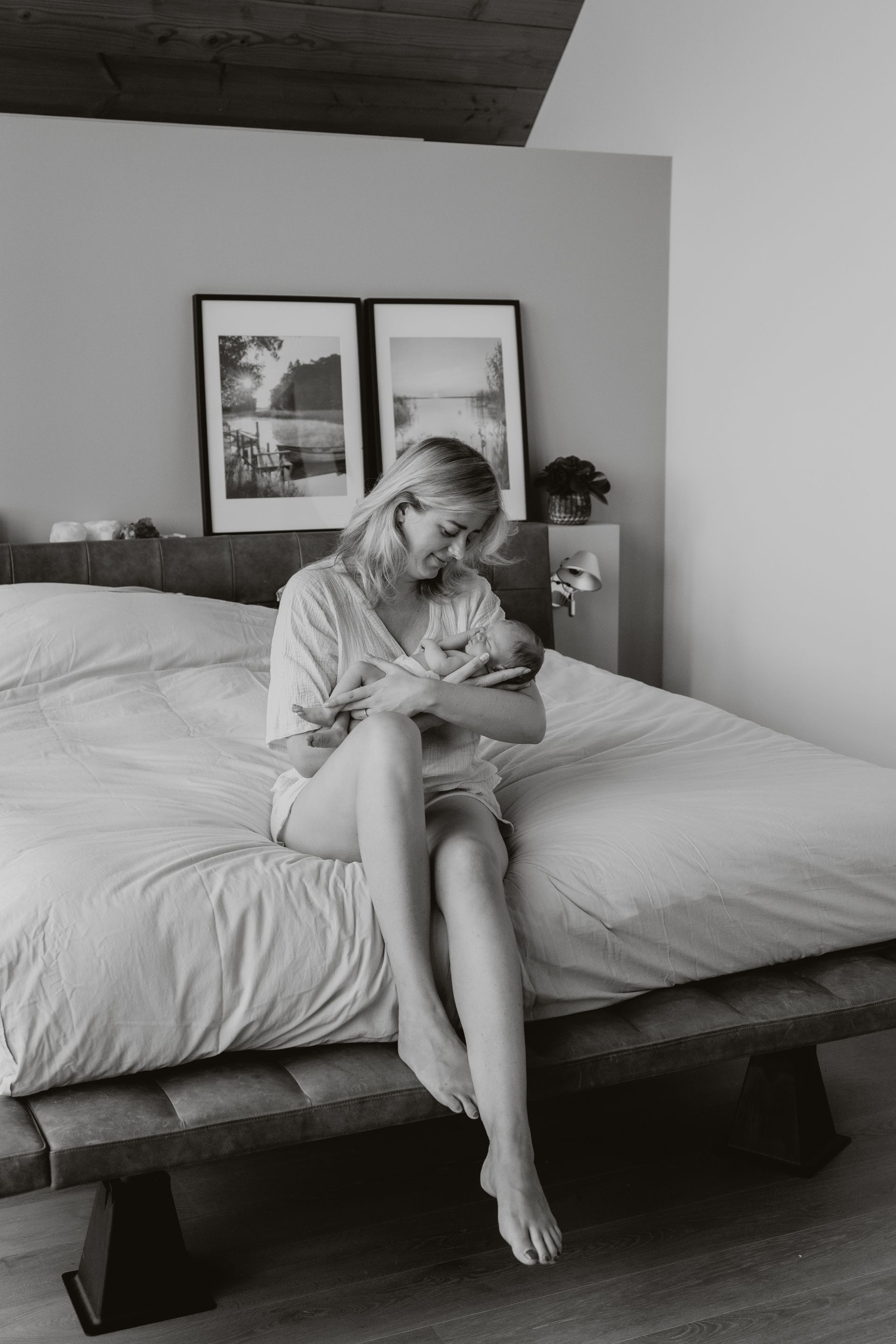 Een vrouw zit op een bed met een baby in haar armen.