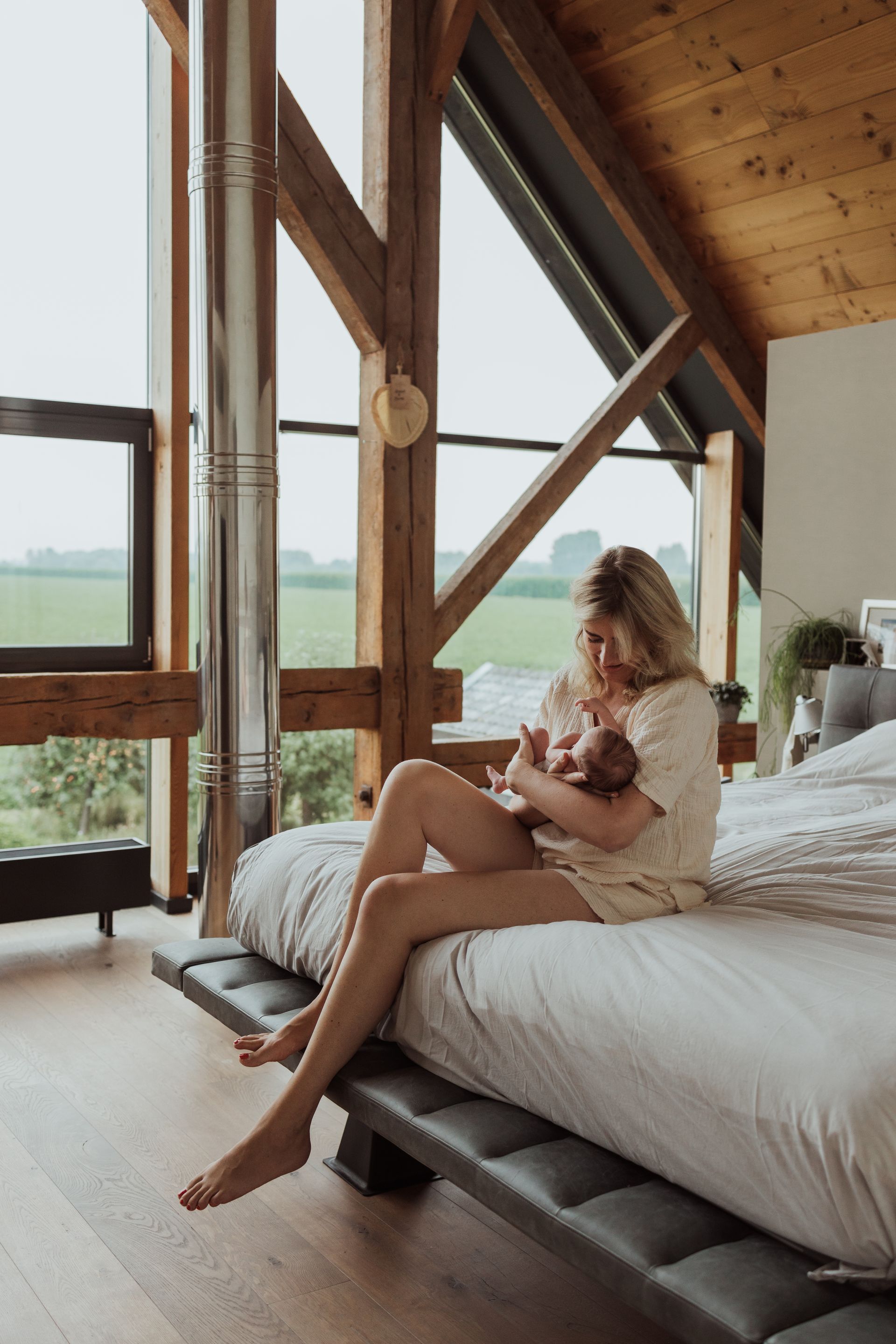 Een vrouw zit op een bed met een baby in haar armen.