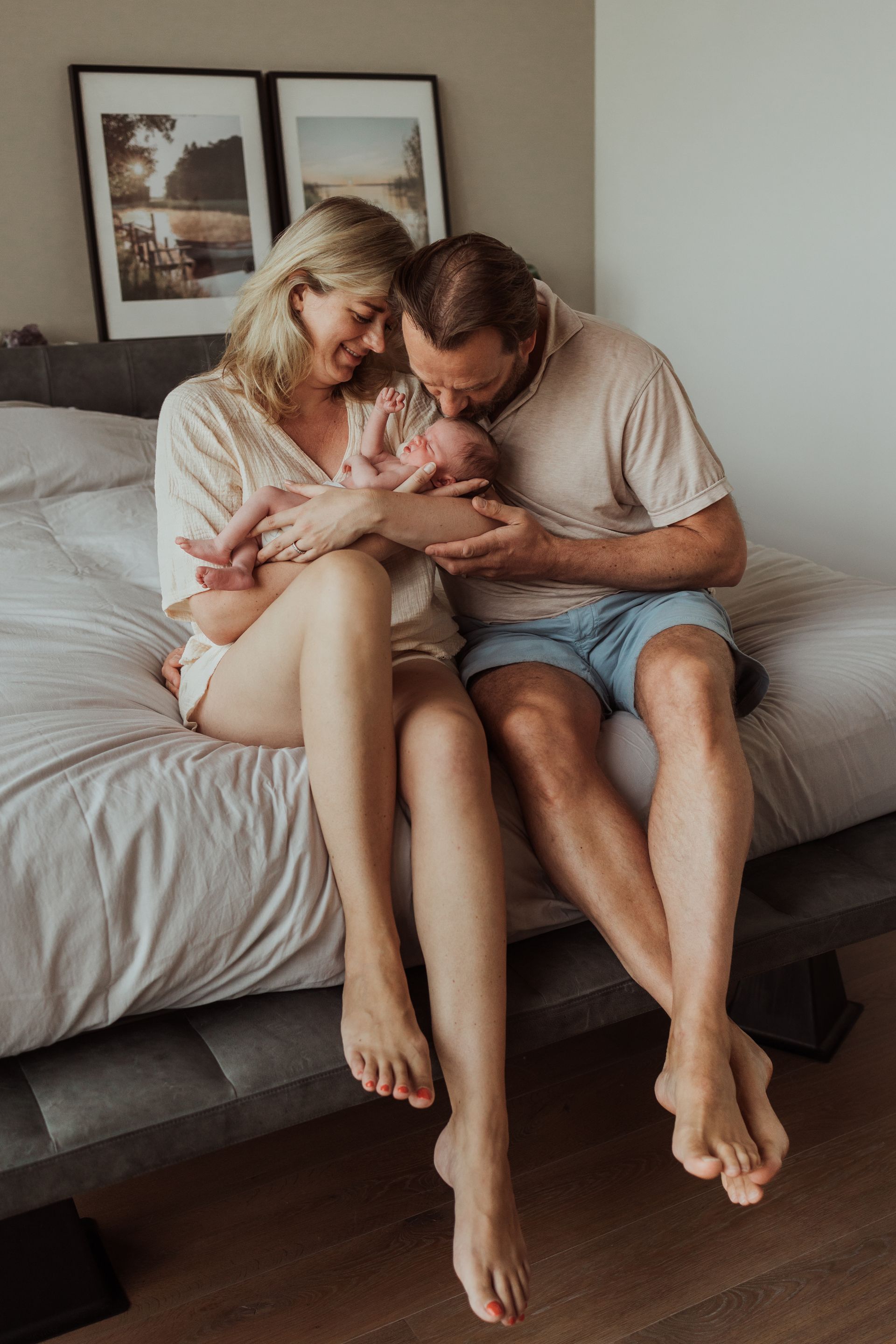 Een man en een vrouw zitten op een bed met een pasgeboren baby.
