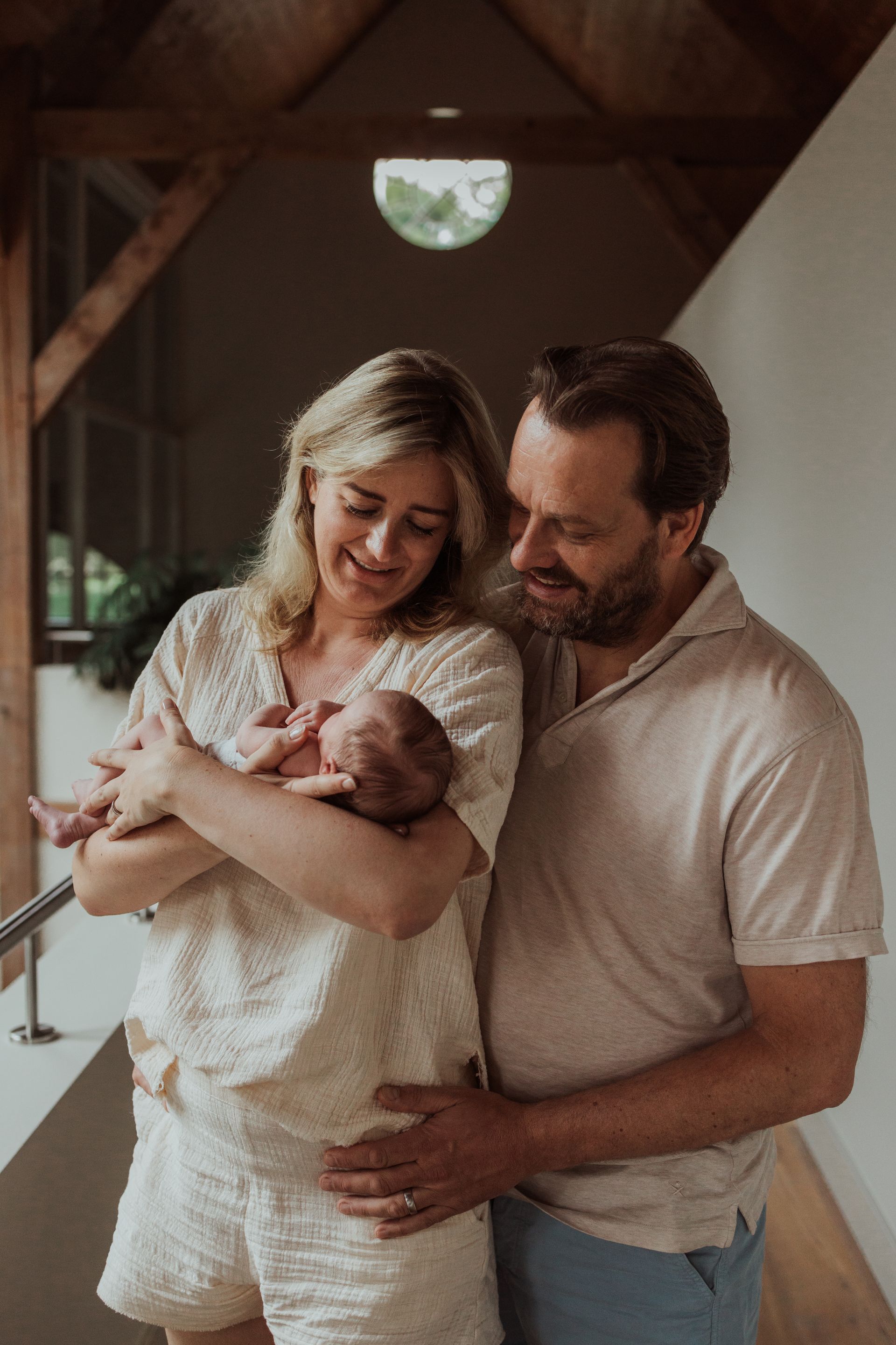 Een man en een vrouw houden een pasgeboren baby in hun armen.