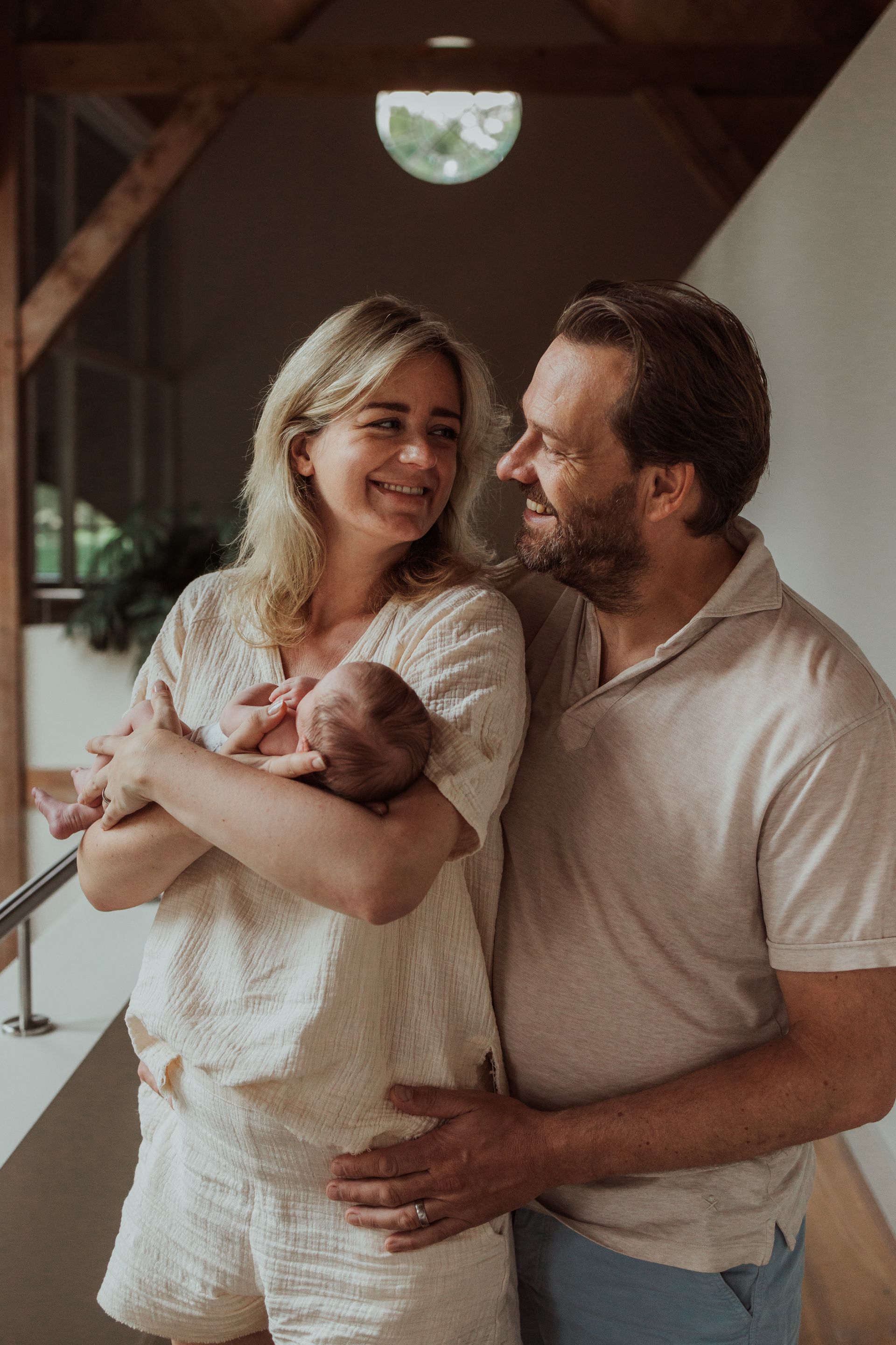 Een man en een vrouw houden een pasgeboren baby in hun armen.
