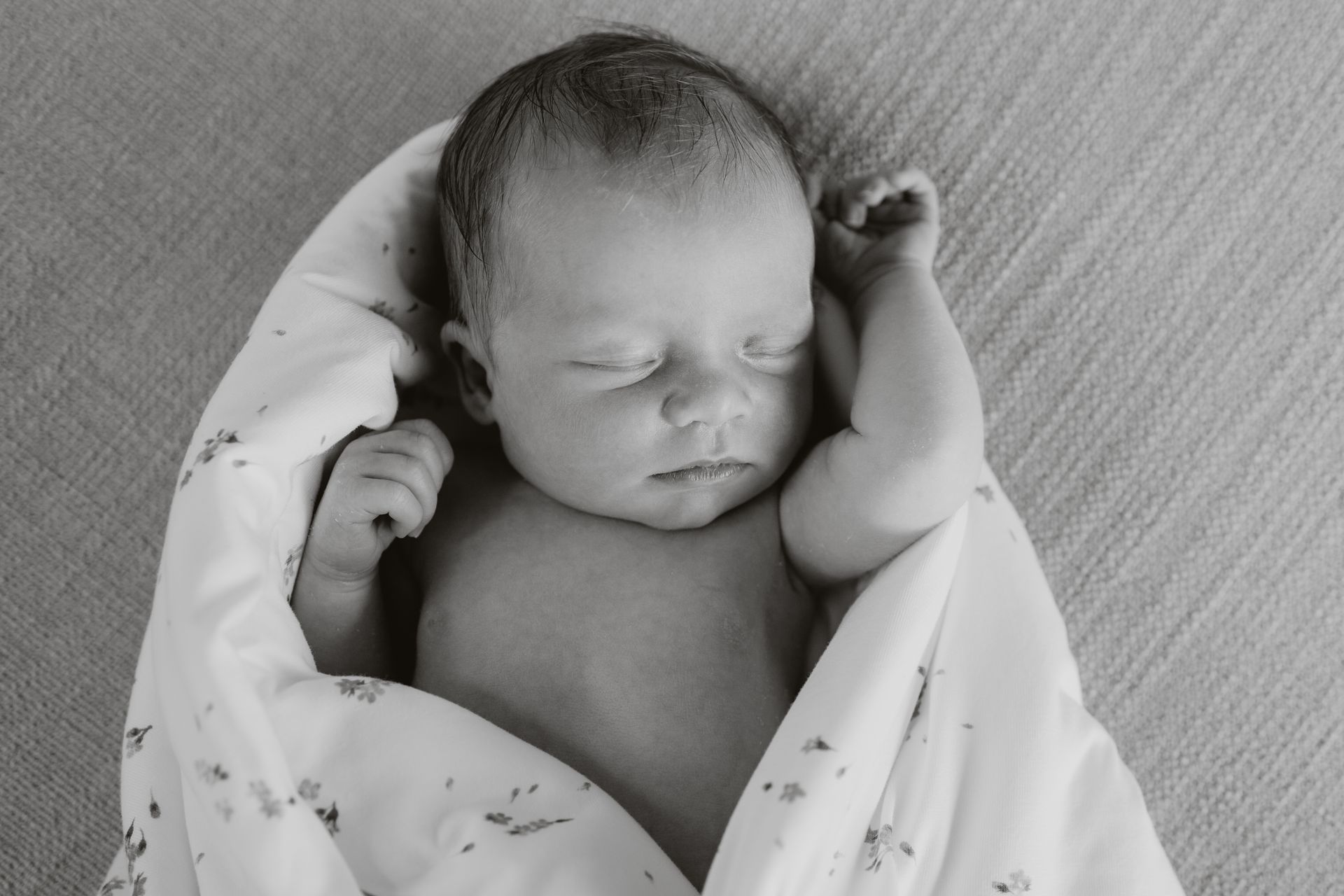 Een zwart-witfoto van een newborn slapend in een dekent