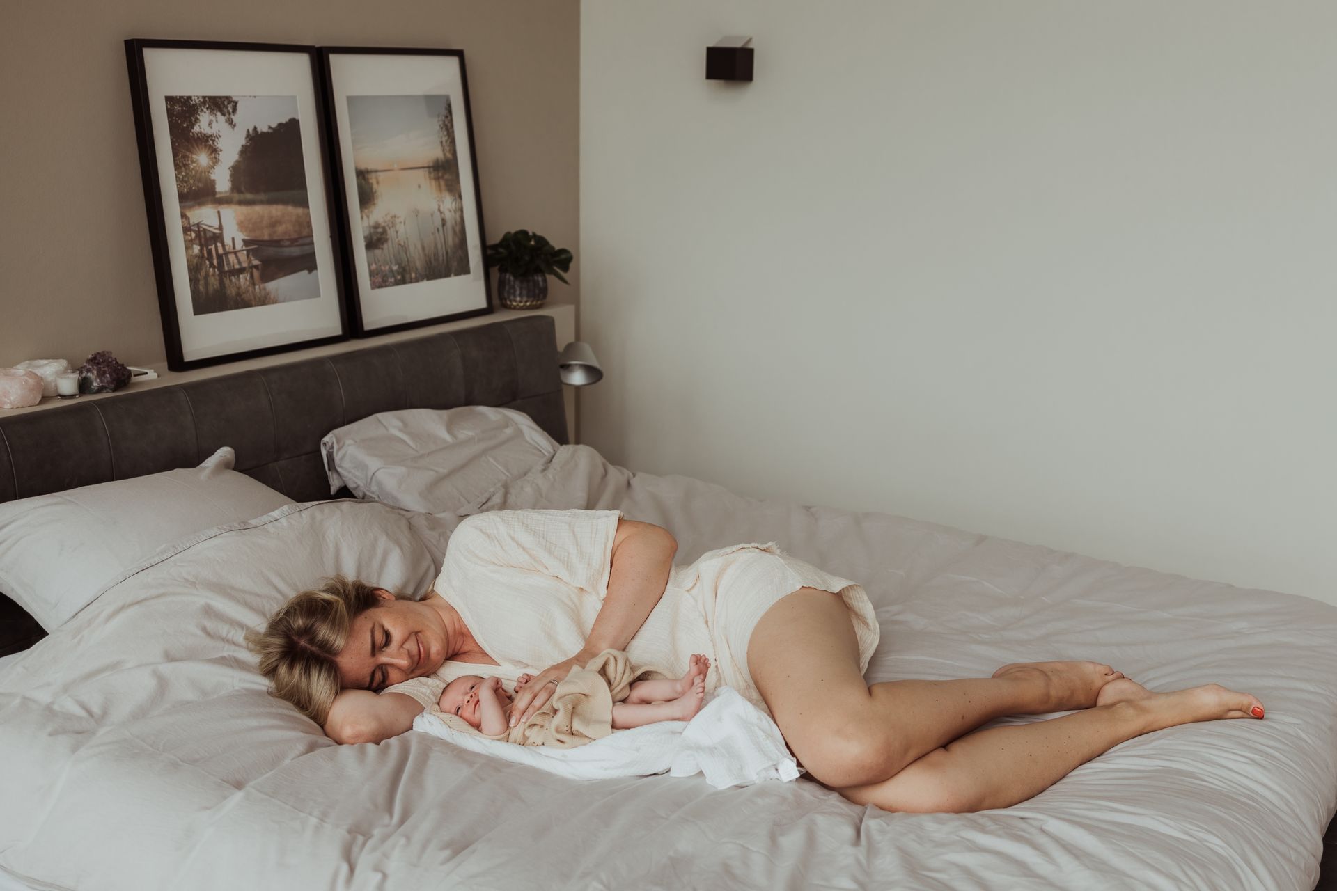 Een vrouw ligt op een bed met een pasgeboren baby in haar armen.