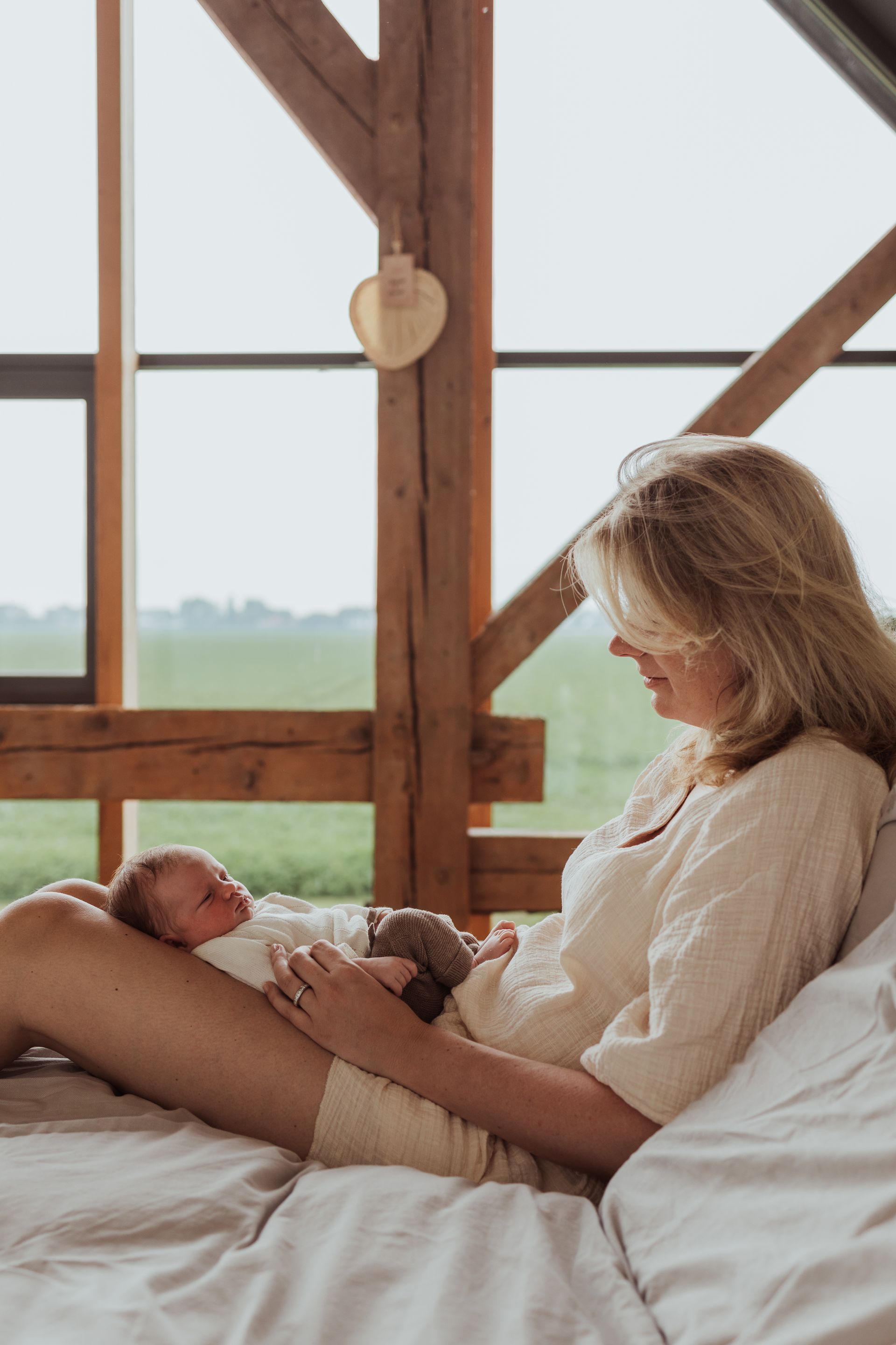 Een vrouw ligt op een bed met een pasgeboren baby in haar armen.