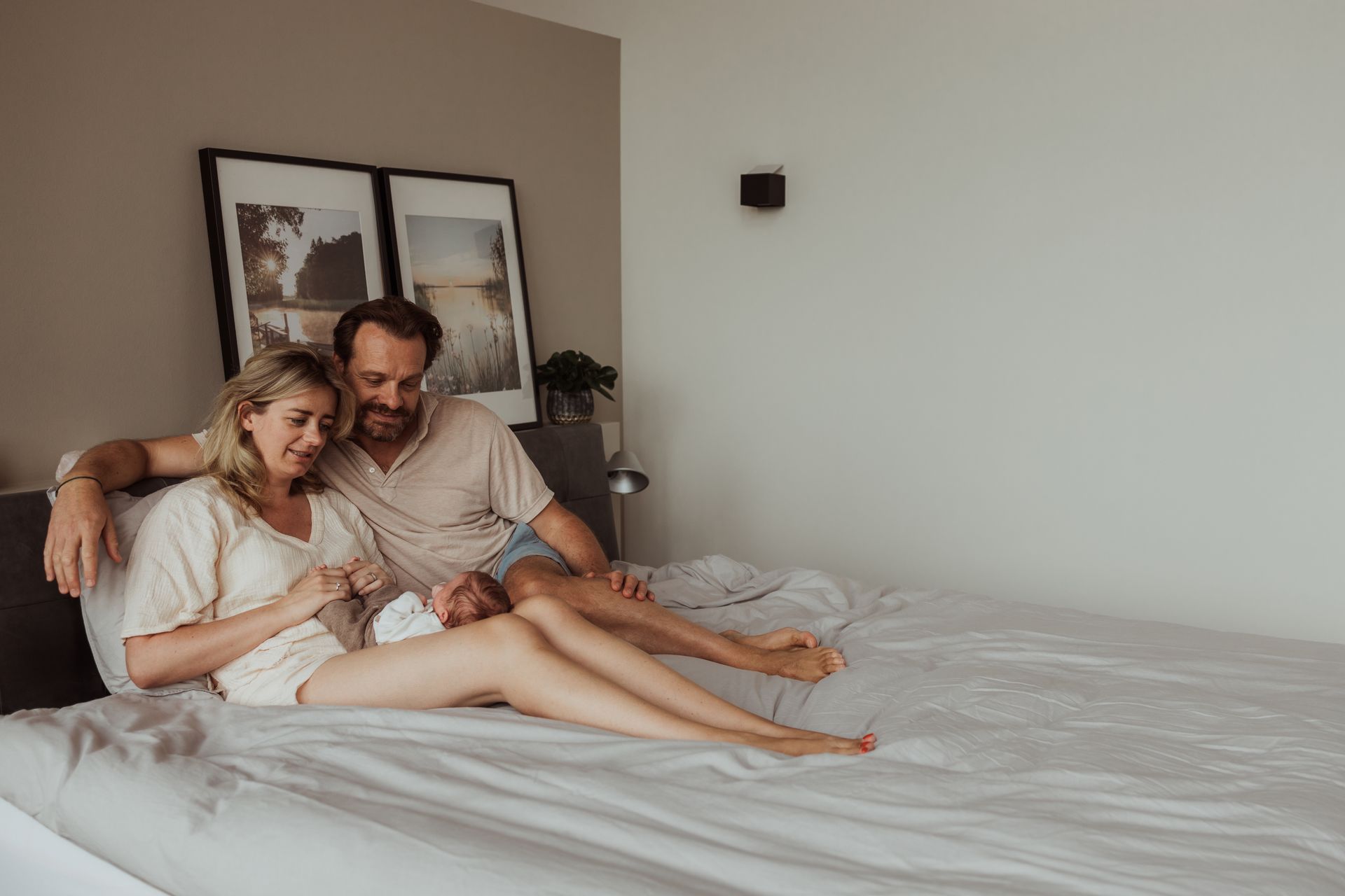 Een man en een vrouw zitten op een bed met een baby.
